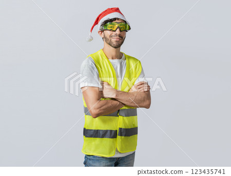 Portrait of a smiling engineer in a christmas hat, Portrait of an engineer in a vest and a christmas hat. Portrait of cheerful engineer in vest and christmas hat with arms crossed. 123435741