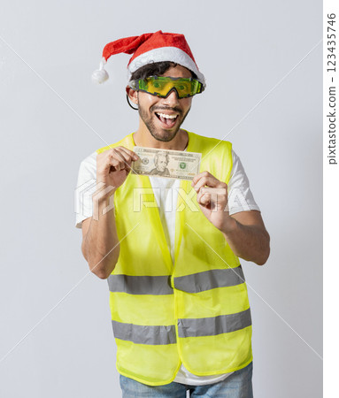 Happy builder engineer with christmas hat holding one dollar bill isolated. Happy christmas engineer showing one dollar bill, Happy engineer in vest and christmas hat showing twenty dollars Happy builder engineer with christmas hat holding one dollar bill isolated. Happy christmas engineer showing one dollar bill, Happy engineer in vest and christmas hat showing twenty dollars 123435746