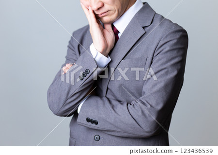 A middle-aged male businessman wearing a gray suit and worried 123436539