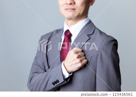 一位身穿灰色西裝、手摀胸口的中年男性商人 123436561
