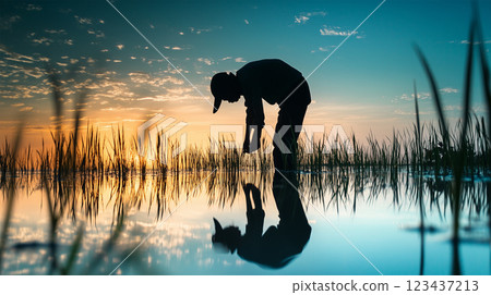 The silhouette of a farmer reflected on the water and a fantastic rice planting scene. 123437213