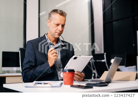 Mature businessman using a tablet to analysis graph company financial in office. 123437427