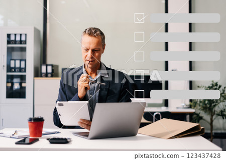 Business performance checklist concept, businessman using tablet and laptop doing online checklist survey, filling out digital form checklist. 123437428
