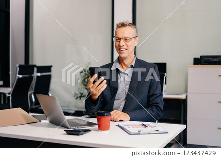 Happy mature businessman holding phone looking at screen waving hands video call friend online. 123437429