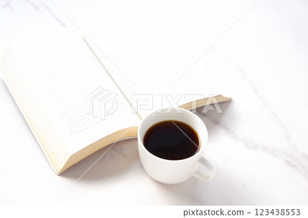 The image of someone reading a paperback while drinking coffee. The image of someone reading a paperback while drinking coffee. 123438553