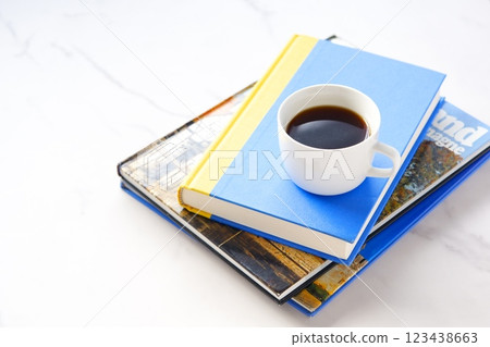 照片中,一個人一邊放鬆、一邊看書,一邊喝著香濃的現煮咖啡。 照片中,一個人一邊放鬆、一邊看書,一邊喝著香濃的現煮咖啡。 123438663