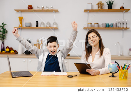 A young woman helps a boy with his lessons using a tablet and a globe. A homeschooling student does his homework with the help of a tutor 123438730