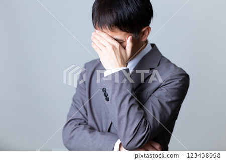 A middle-aged male businessman wearing a gray suit and worried A middle-aged male businessman wearing a gray suit and worried 123438998