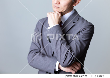 A middle-aged male businessman wearing a gray suit and worried A middle-aged male businessman wearing a gray suit and worried 123438999