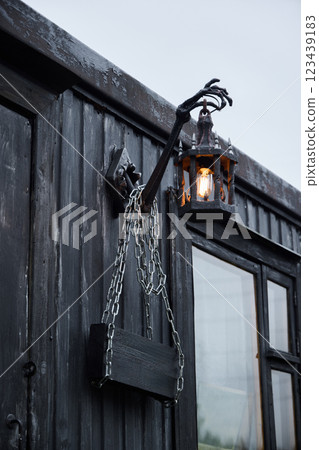 A Mysterious Lantern with an Intricate Chain and a Hand Structure is Adorned on a Dark Wall A Mysterious Lantern with an Intricate Chain and a Hand Structure is Adorned on a Dark Wall 123439183