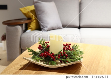 This festive candle centerpiece, adorned with greenery and berries, suits any holiday gathering 123439211