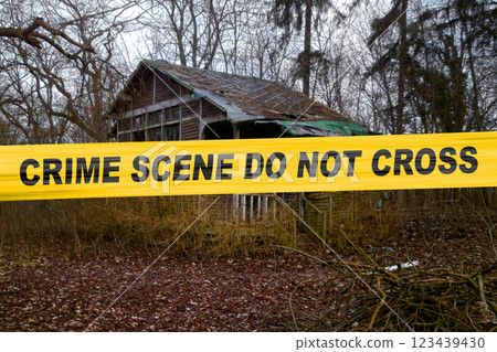 American police tape in front of an abandoned cabin in the woods 123439430