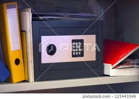 Safe box on a shelf amongst binders and notebooks Safe box on a shelf amongst binders and notebooks 123441049