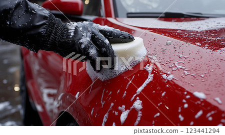 Gloved hand cleaning red car with sponge 123441294