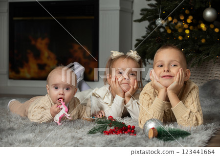 Overjoyed small children in santa hats have fun unpack wrapped presents on merry Christmas morning near fir tree. 123441664