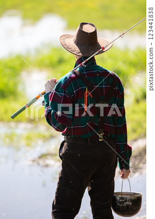 An adult man with a fishing rod goes fishing. 123441838