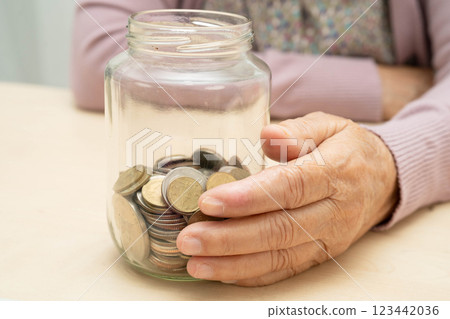 Retired Asian elderly woman counting coins money and worry about monthly expenses and treatment fee payment. Retired Asian elderly woman counting coins money and worry about monthly expenses and treatment fee payment. 123442036