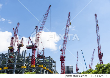 Low-angle view of cranes and steel structures of building construction with a blue sky background in Taiwan. Low-angle view of cranes and steel structures of building construction with a blue sky background in Taiwan. 123442595