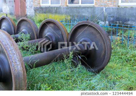 Rusty train wheels lie tilted on green grass, is under restoration awaiting inspection Rusty train wheels lie tilted on green grass, is under restoration awaiting inspection 123444494