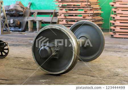 Train metal wheels lie on ground in a workshop, surrounded by machinery is under restoration 123444499