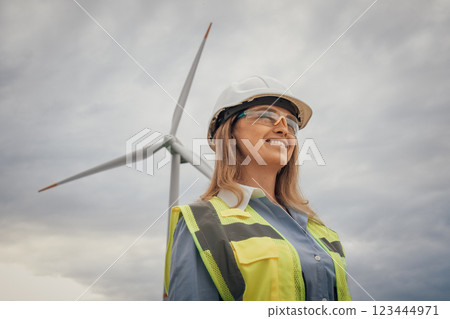 An Empowered Woman in Safety Gear at a Wind Farm, Representing Future Careers in Construction and Engineering, Contributing to Ecology and Sustainability in Industry with Confidence and Inspiration 123444971