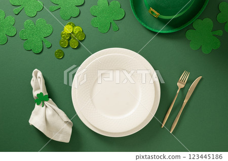 St Patrick's Day table setting with white plate and shamrock, clover leaves and coins on green background. View from above. St Patrick's Day table setting with white plate and shamrock, clover leaves and coins on green background. View from above. 123445186