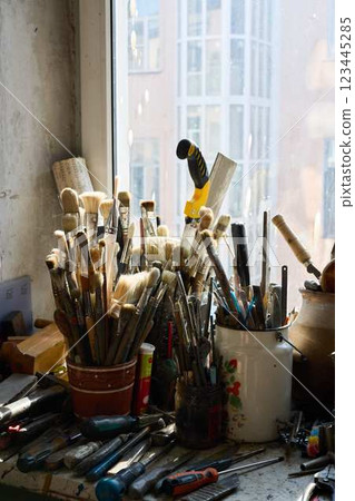 An Artistic Workspace Featuring Variety of Brushes and Essential Tools for Creativity and Crafting 123445285