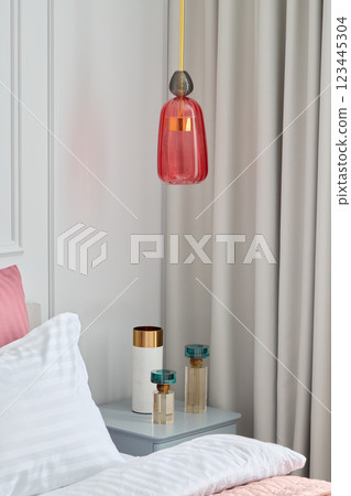 A modern bedroom featuring a colorful pendant light and decorative elements that enhance its appeal 123445304