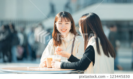 兩名女子在露台喝酒時微笑著聊天 兩名女子在露台喝酒時微笑著聊天 123445830