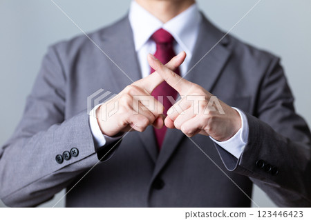一位身穿灰色西裝的中年男性商人做出十字架手勢 123446423