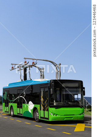 Electric bus at a stop is charged by pantograph. Sola panels in the background Electric bus at a stop is charged by pantograph. Sola panels in the background 123446468