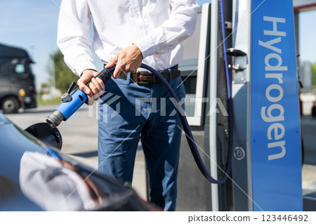Man holds a hydrogen fueling nozzle on a hydrogen filling station. Refueling car with hydrogen fuel. Man holds a hydrogen fueling nozzle on a hydrogen filling station. Refueling car with hydrogen fuel. 123446492