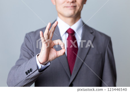 A middle-aged male businessman wearing a gray suit making a circle sign 123446540