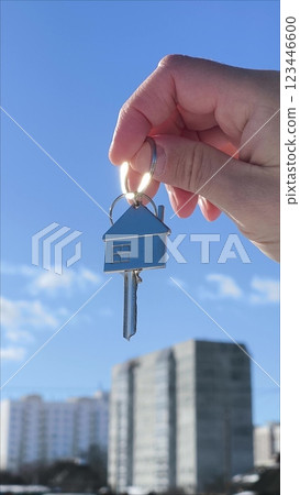 Holding house keys on house shaped keychain concept for buying a new home. Vertical - the key to the house is in the hands of the agent. The concept of building a new house. Holding house keys on house shaped keychain concept for buying a new home. Vertical - the key to the house is in the hands of the agent. The concept of building a new house. 123446600