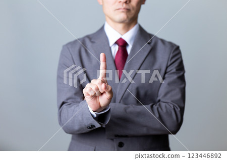 A middle-aged male businessman wearing a gray suit and pointing his index finger 123446892