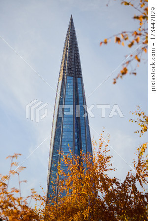 A stunning tall skyscraper stands tall and gracefully amidst the vibrant autumn leaves in the city 123447029