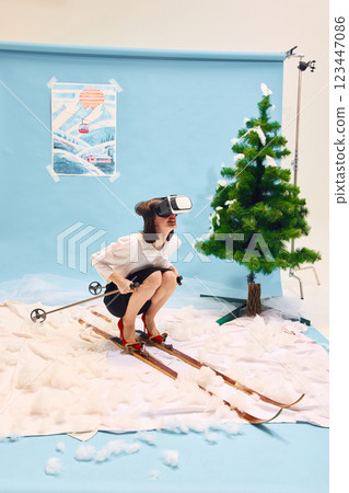 Woman in business clothes wearing VR headset sitting on skis against abstract winter background. Woman in business clothes wearing VR headset sitting on skis against abstract winter background. 123447086