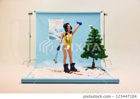 Woman in gold swimsuit and ski boots taking selfie with smartphone against winter-themed backdrop. Woman in gold swimsuit and ski boots taking selfie with smartphone against winter-themed backdrop. 123447104