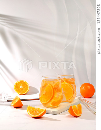 Orange juice and oranges on elegant kitchen table with long hard shadows. Modern still life with citrus fruits, minimal detox diet concept, summer vitamin drinks, selective focus 123447208