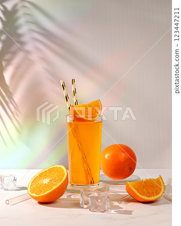 Orange juice and oranges on sunny kitchen table with long hard shadows. Modern still life with citrus fruits, minimal detox diet concept, summer vitamin drinks, selective focus, 123447211