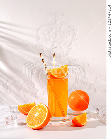 Modern still life with citrus fruits, orange juice and oranges on elegant kitchen table with long hard shadows, minimal detox diet concept, summer vitamin drinks, selective focus 123447214