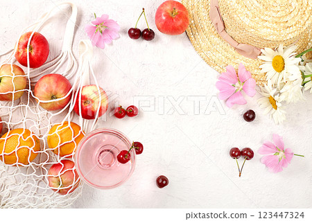 Summer fashion banner on a bright background. Straw hat, fruits in an eco-bag, refreshing alcoholic drinks and chamomile flowers on a sunny table. Vacation and travel concept, outdoor camping and Summer fashion banner on a bright background. Straw hat, fruits in an eco-bag, refreshing alcoholic drinks and chamomile flowers on a sunny table. Vacation and travel concept, outdoor camping and 123447324