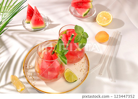 Ice cold homemade lemonade or cocktail with mint, watermelon and fruit, a recipe for a refreshing summer drink. Two glasses with fruit drink on sunny table, detox diet and weight loss concept, menu Ice cold homemade lemonade or cocktail with mint, watermelon and fruit, a recipe for a refreshing summer drink. Two glasses with fruit drink on sunny table, detox diet and weight loss concept, menu 123447352