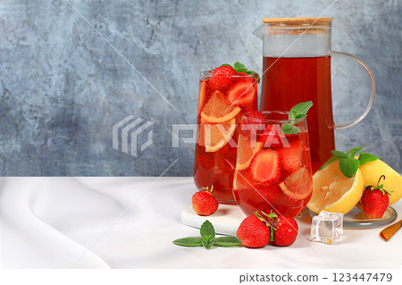 Iced strawberry tea or mint lemon smoothie is a refreshing summer drink recipe. Glass with berry fruit lemonade on a light concrete table, detox diet and weight loss concept, restaurant menu 123447479