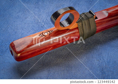 detail of native American style flute with fetish handcrafted from aromatic cedar wood against art paper 123449142