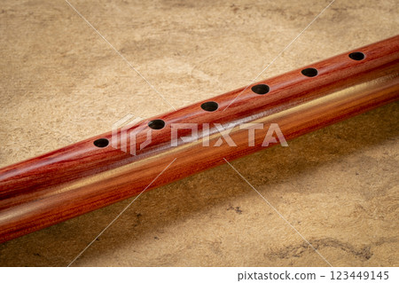 native American style flute handcrafted from aromatic cedar wood against art paper native American style flute handcrafted from aromatic cedar wood against art paper 123449145