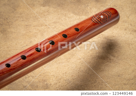 native American style flute handcrafted from aromatic cedar wood against art paper native American style flute handcrafted from aromatic cedar wood against art paper 123449146