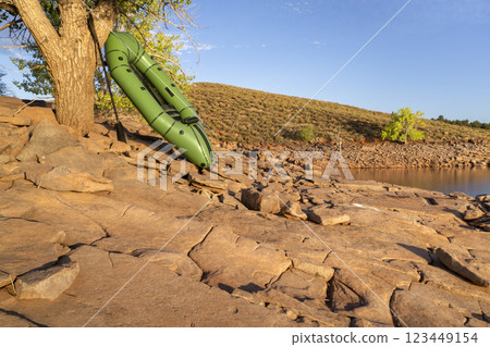 inflatable packraft (one-person light raft used for expedition or adventure racing) with a paddle on a lake shore in Colorado, on Horsetooth Reservoir inflatable packraft (one-person light raft used for expedition or adventure racing) with a paddle on a lake shore in Colorado, on Horsetooth Reservoir 123449154