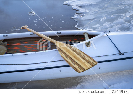 decked expedition canoe with a wooden paddle on an icy lake shore decked expedition canoe with a wooden paddle on an icy lake shore 123449583