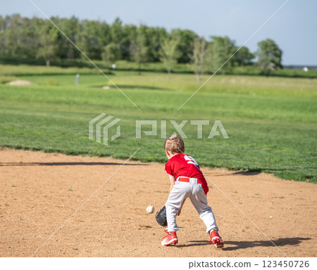 Young caucasian boy fielding a ground ball during a T-ball game Young caucasian boy fielding a ground ball during a T-ball game 123450726